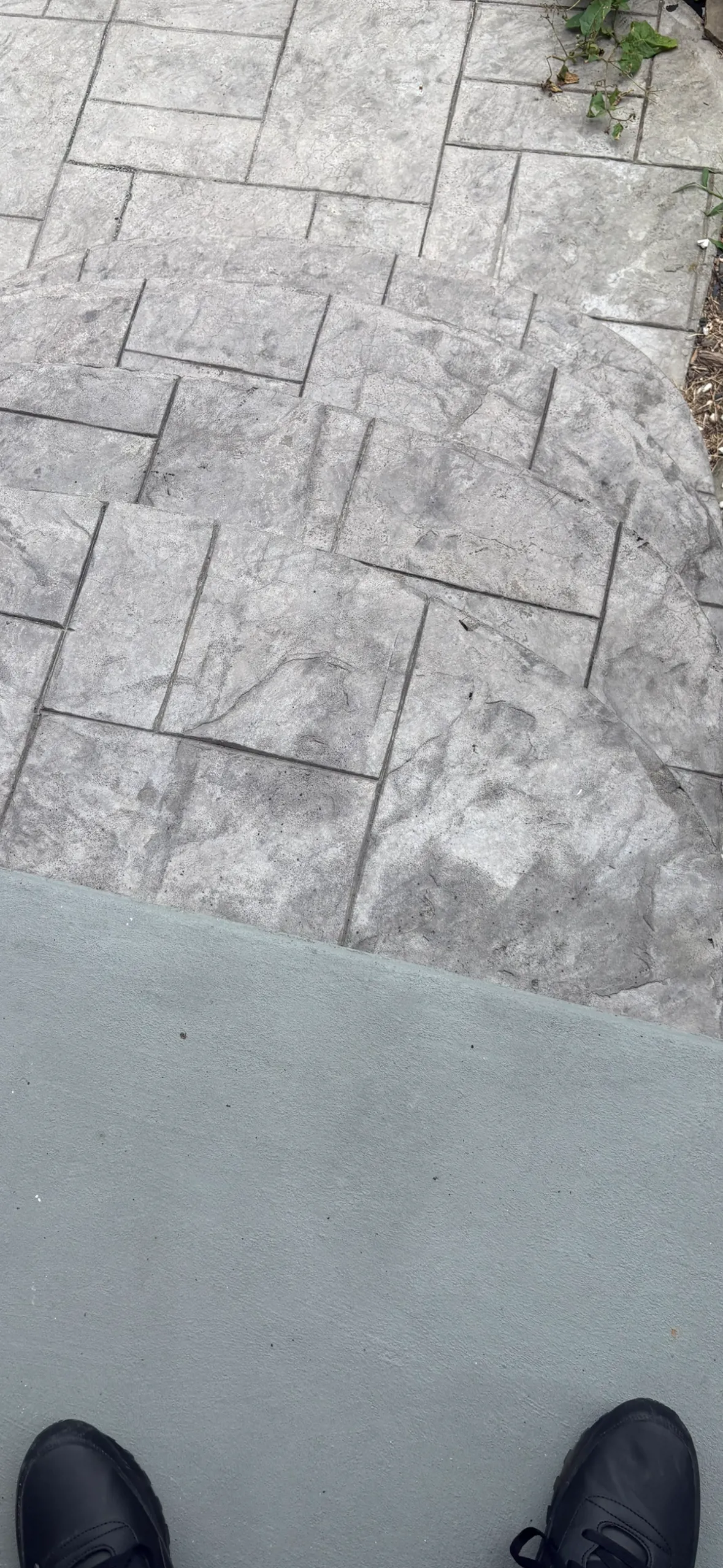Curved stamped concrete steps in a gray ashlar stone pattern above a smooth concrete landing.